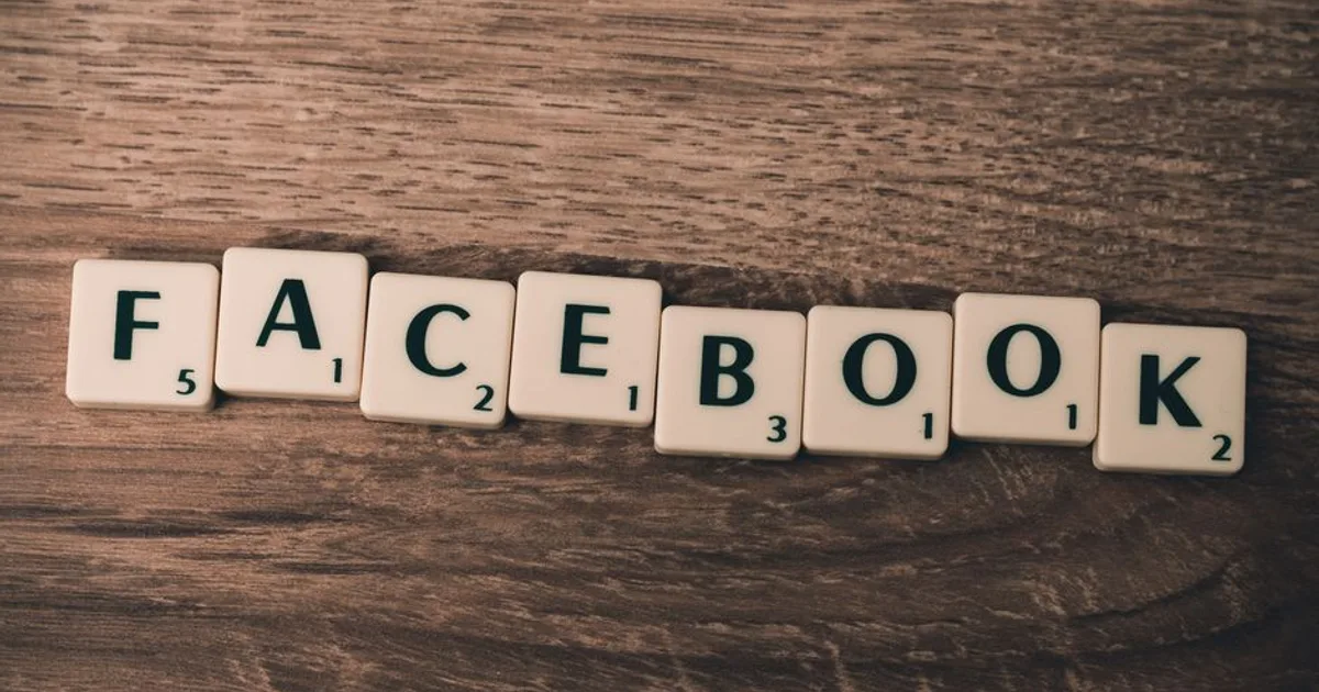 Scrabble tiles spelling 'Facebook' on a wood background, symbolizing social media.